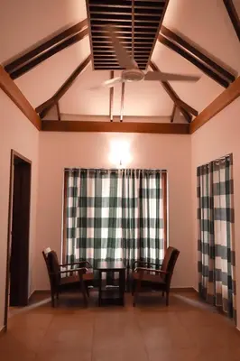 a living room with chairs and a ceiling fan at Century Village Resort in Mananthavady