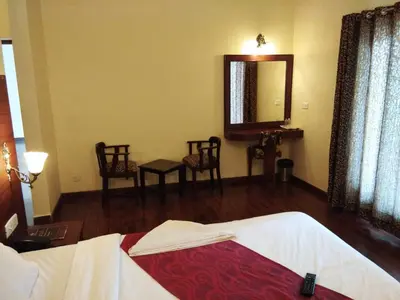 a bedroom with a bed and a mirror and chairs at Berry Hills Resort in Ooty