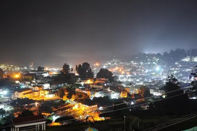 a view of a city at night with lights at Rosepark Residency in Ooty