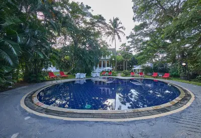 a large swimming pool with red chairs and trees at Royal Orchid Metropole Mysore in Mysore