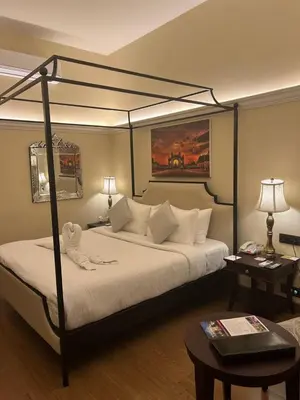 a bedroom with a bed with a black frame and a table at Royal Orchid Metropole Mysore in Mysore