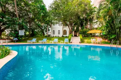 a large swimming pool with chairs and an umbrella at Royal Orchid Brindavan Garden Palace & Spa Mysore in Belagula