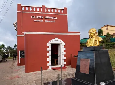 a statue of a man in front of a red building at Teanest Nightingale by Nature Resorts and Stays in Kotagiri