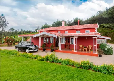 a red house with a car parked in front of it at Teanest Nightingale by Nature Resorts and Stays in Kotagiri