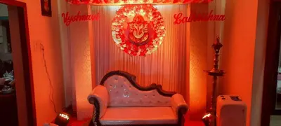 a room with a chair and a wreath on the wall at Krishnendu Homestay outer ring road north nada guruvayur in Guruvāyūr