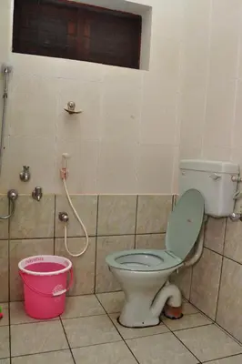 a bathroom with a toilet and a bucket at Krishnendu Homestay outer ring road north nada guruvayur in Guruvāyūr