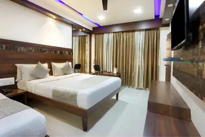 a hotel room with a bed and a television at Mannars Deluxe Lodge in Mysore