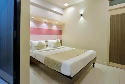 a bedroom with a bed with a pink and white wall at Mannars Deluxe Lodge in Mysore