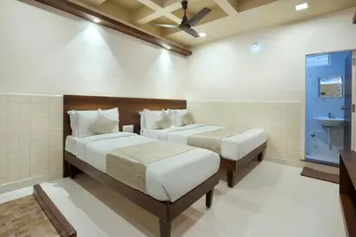 a bedroom with two beds and a sink in it at Mannars Deluxe Lodge in Mysore