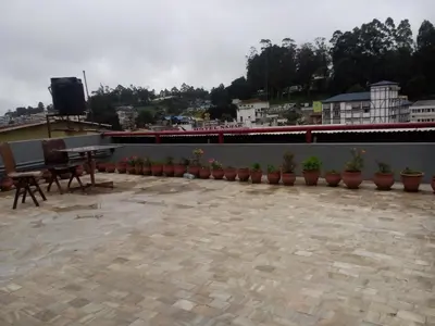 a patio with a table and potted plants on a roof at Hotel Preethi Palace in Ooty