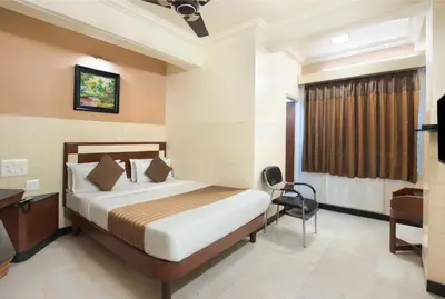 a bedroom with a bed and a desk and a chair at Mannars Yatri Nivas Hotel in Mysore