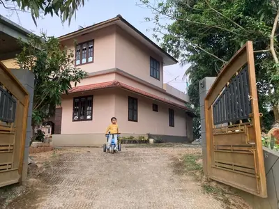 a young boy riding a bike in front of a house at Wayanad Homestay in Kalpetta