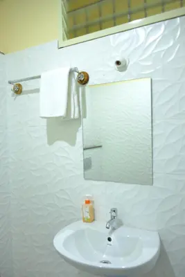 a white bathroom with a sink and a mirror at Golden Nest in Mysore