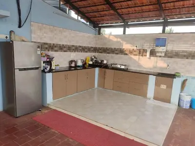 a large kitchen with a counter and a refrigerator at Golden Nest in Mysore