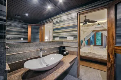 a bathroom with a sink and a bedroom at Elixir Hills Suites Resort and Spa in Munnar