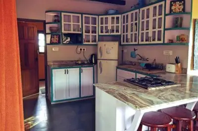 a kitchen with white cabinets and a counter top at Stumpfields in Ooty