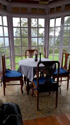 a dining room with a table and chairs and windows at Stumpfields in Ooty