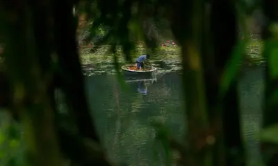 a man in a small boat in the water at Vista Del Lago in Ambalavayal