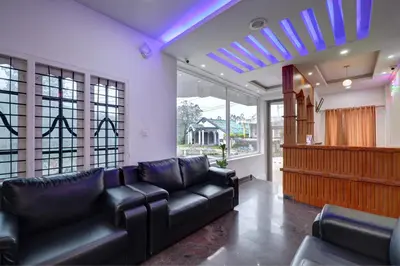 a living room with a black leather couch and windows at Kurinji Wanderlust Resort Munnar in Munnar