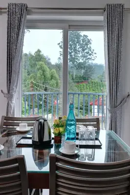 a dining room table with a view of a window at Kurinji Wanderlust Resort Munnar in Munnar