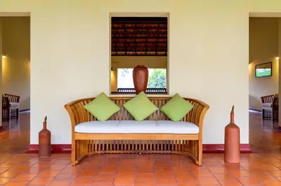 a bench with green pillows on it in a room at Windermere River House in Neriyamangalam