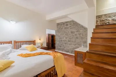 a bedroom with a large bed and a stone wall at Windermere River House in Neriyamangalam