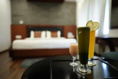 two drinks on a table in a room with a bed at Four N Square Residency in Palakkad