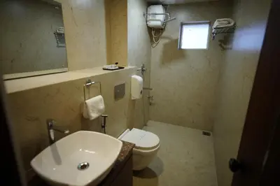 a bathroom with a sink and a toilet and a mirror at Four N Square Residency in Palakkad