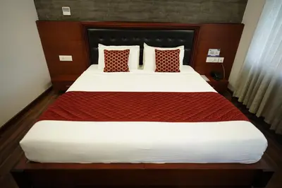 a large bed with red and white sheets and pillows at Four N Square Residency in Palakkad