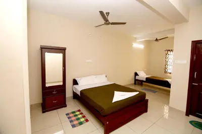 a bedroom with a bed and a dresser and a mirror at Aditya Residency in Pollāchi