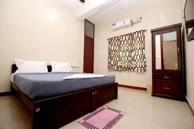 a bedroom with a bed with blue sheets and a mirror at Aditya Residency in Pollāchi