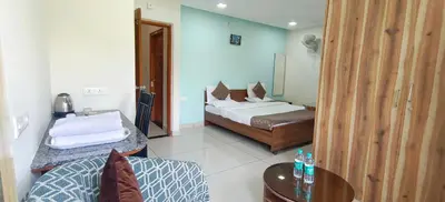 a bedroom with two beds and a table and a chair at Sugamya Corner Guesthouse in Mysore