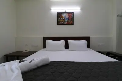 a bedroom with a large bed with white sheets and pillows at Hotel Paradise Inn in Tiruppūr