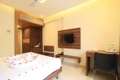 a room with a bed and a desk and a tv at Sandesh Pride in Mysore