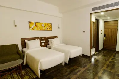 a hotel room with two beds and a chair at Lemon Tree Hotel Coimbatore in Coimbatore