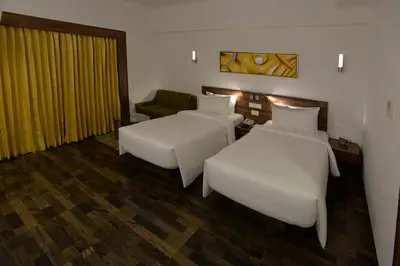a hotel room with two beds and a couch at Lemon Tree Hotel Coimbatore in Coimbatore