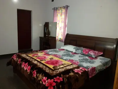 a bedroom with a bed with a floral comforter at Holidays and Celebrations in Kodaikānāl
