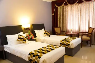 a hotel room with two beds and a table and chairs at Hotel Gopalapuram International in Pollāchi
