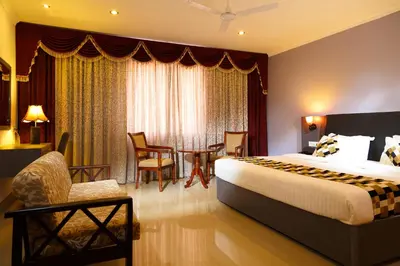 a hotel room with a bed and a table and chairs at Hotel Gopalapuram International in Pollāchi