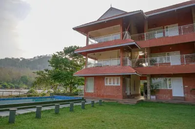 a red brick building with a swimming pool in front of it at Willow Heights in Athirappilly