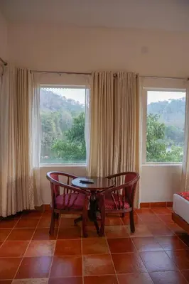 a room with a table and two chairs and two windows at Willow Heights in Athirappilly