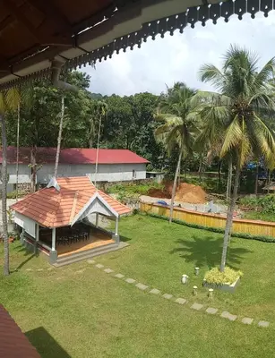 a house with a roof on a field with palm trees at Willow Heights in Athirappilly