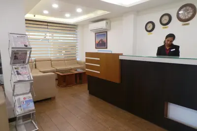 a woman standing at a counter in a waiting room at SAAS Residency in Kozhikode