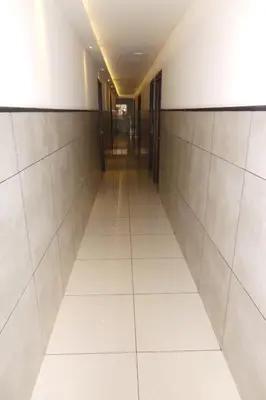 an empty hallway in a building with white tiles at SAAS Residency in Kozhikode