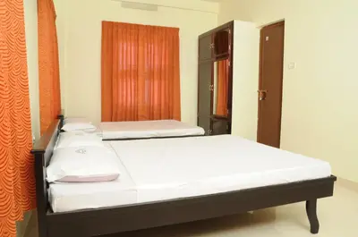a bedroom with two beds and a window at Anandkrishna Residency in Guruvāyūr