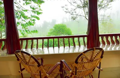 two chairs sitting on a balcony looking out of a window at Green Garden Wayanad Villas in Vayittiri