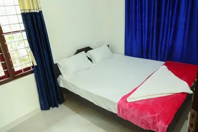 a bedroom with a large bed with blue curtains at Green Garden Wayanad Villas in Vayittiri