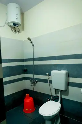 a bathroom with a white toilet and a red object at Green Garden Lotus Villa in Kaniyāmbetta