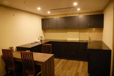 a kitchen with black cabinets and a wooden table at U C plaza in Perintalmanna