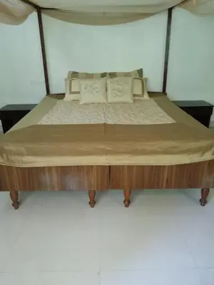 a bed with a wooden frame and pillows on it at Kwality Estate in Madikeri